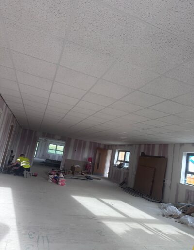 Commercial fit-out in progress showing suspended ceiling and metal stud partitioning work