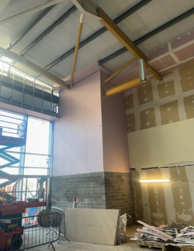 Drylining partition wall under construction in a large industrial unit